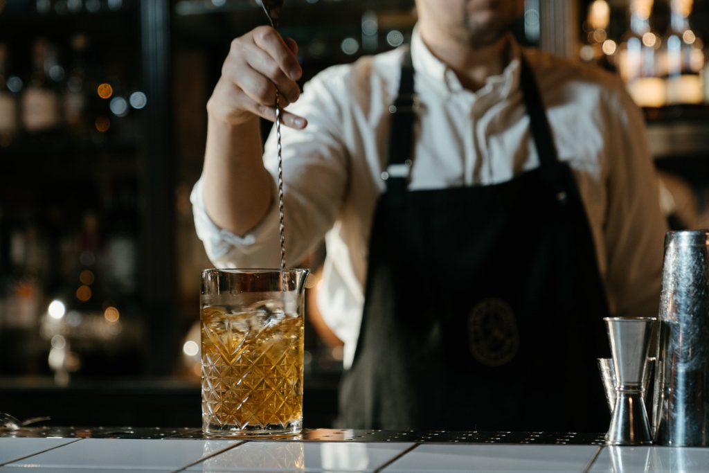 A bartender stirring a cocktail with a bar spoon